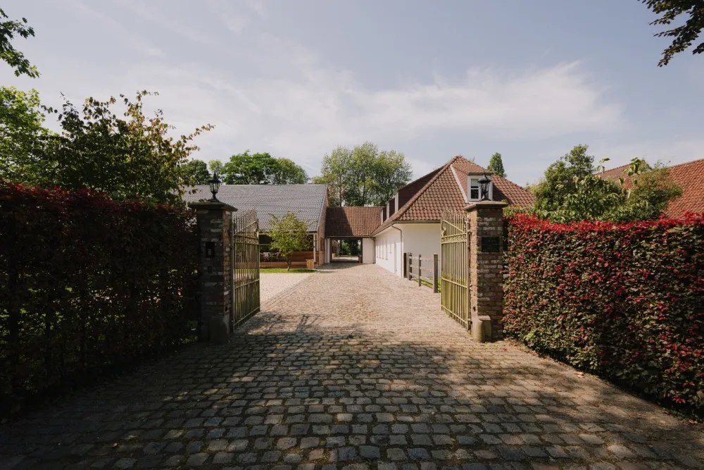 Een klassiek ijzeren hek sluit het domein van De Baian af van de Krauwerstraat.